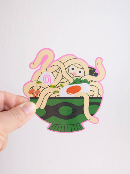 Ramen Vinyl Sticker — illustration of a ramen bowl with noodle limbs and a small peeking face, held between two fingers