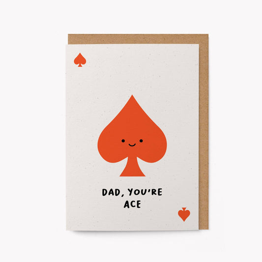 Cream greeting card with a large smiling red spade card-suit symbol and the text 'Dad, You're Ace,' kraft envelope alongside