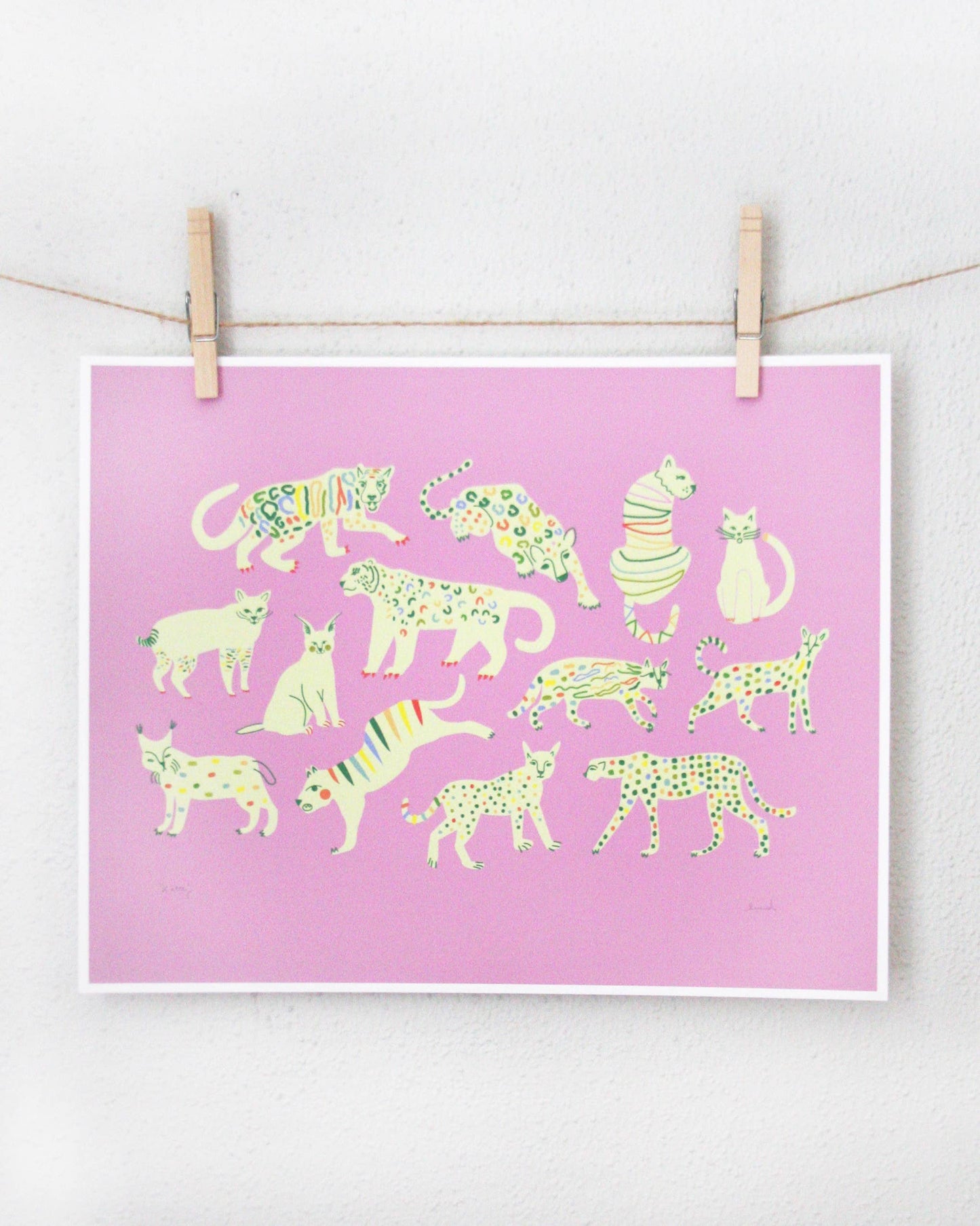 Art print of cream-coloured wild cats with rainbow spot patterns on a pink background, clipped to a string — PABOOM
