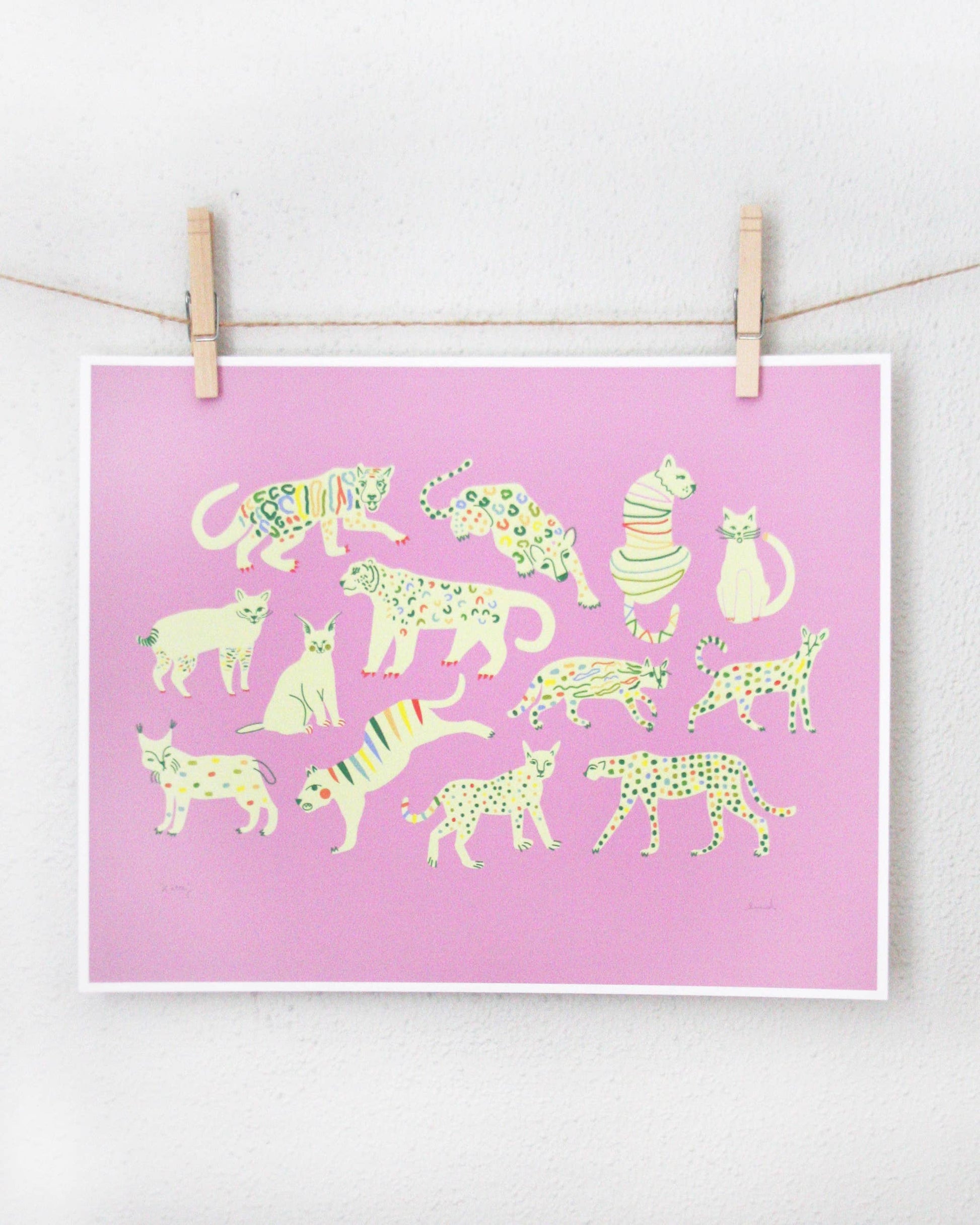 Art print of cream-coloured wild cats with rainbow spot patterns on a pink background, clipped to a string — PABOOM