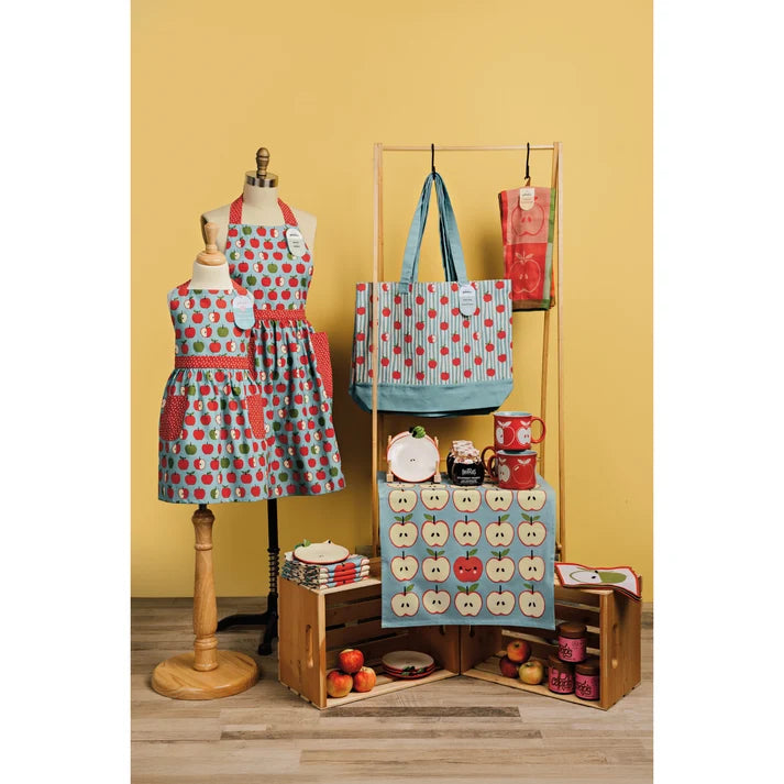 Yellow-toned lifestyle scene styled with an apple-print jacquard towel, matching apron, tote bag, and mugs – PABOOM