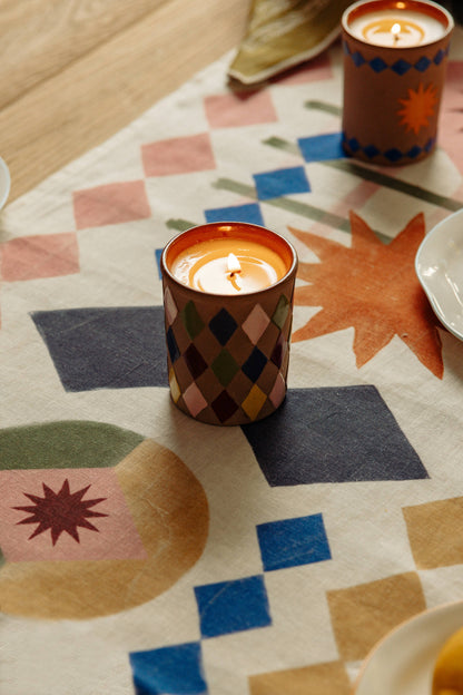 Decorative candles in patterned holders on a colorful quilt