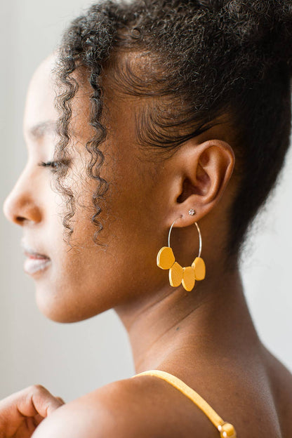 Close-up of mustard yellow leather petal hoop earring detail