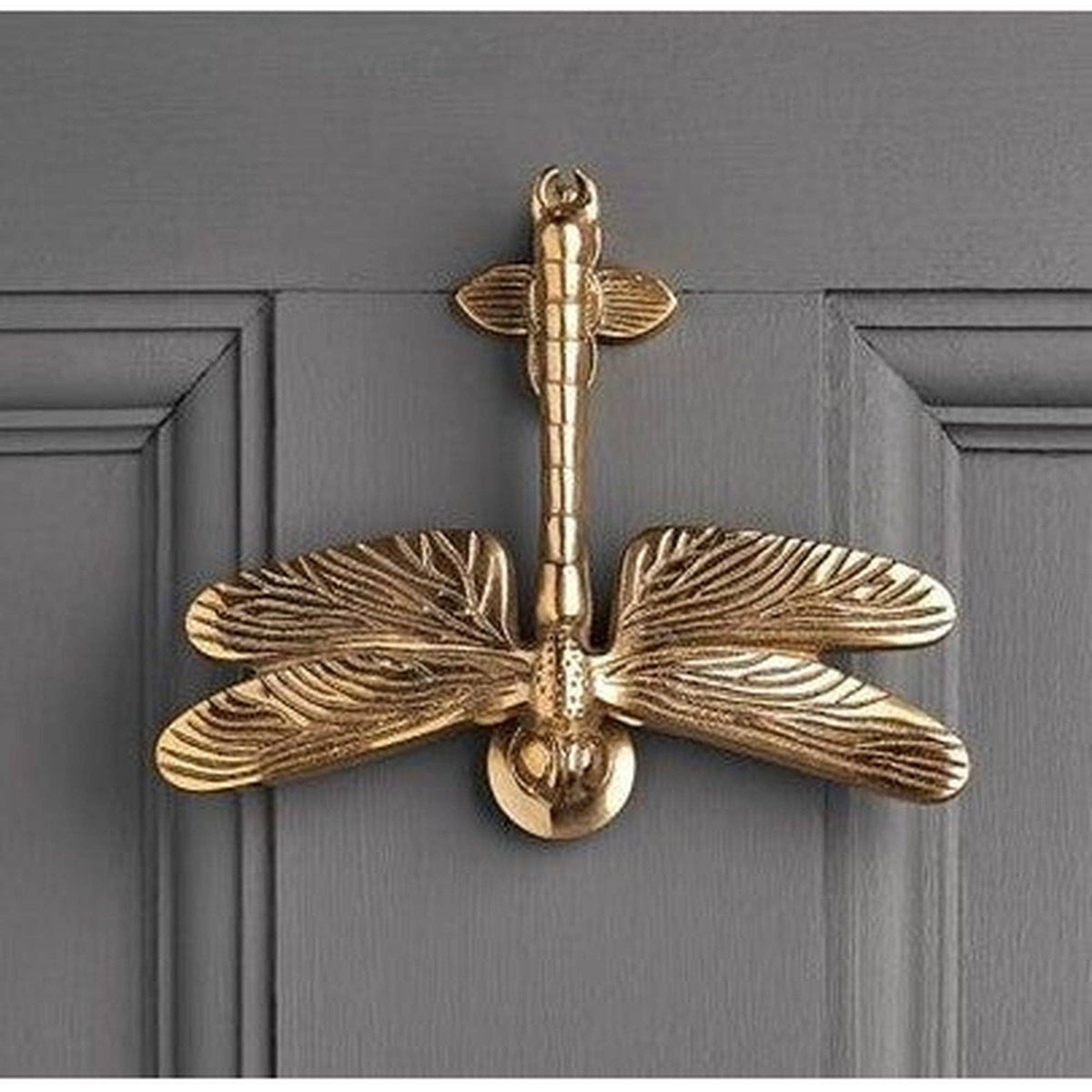 Brass-toned cast iron dragonfly door knocker mounted on a grey door - PABOOM