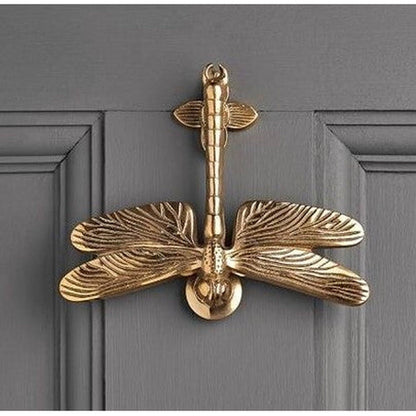 Brass-toned cast iron dragonfly door knocker mounted on a grey door - PABOOM