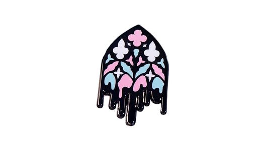 Black nickel enamel pin shaped like a gothic cathedral window with pink, white, and blue stained-glass pattern and a dripping black base