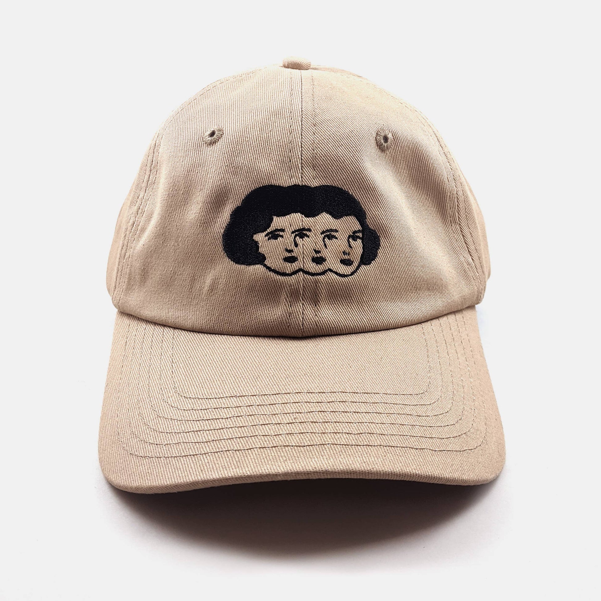 Tan dad hat with an embroidered design of three faces sharing one head of hair - PABOOM
