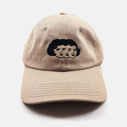 Tan dad hat with an embroidered design of three faces sharing one head of hair - PABOOM