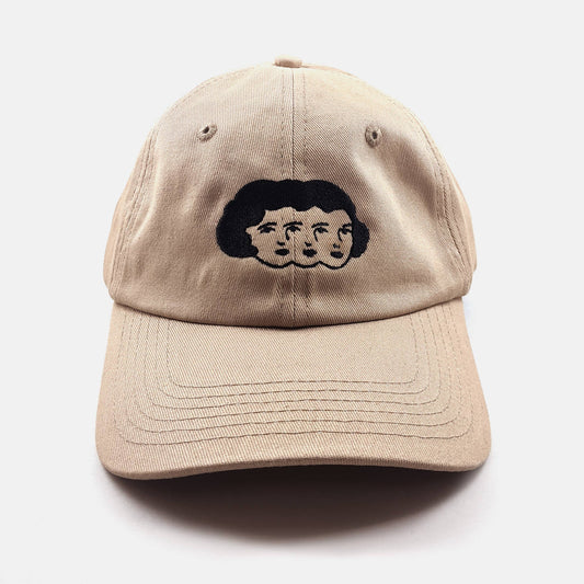 Tan dad hat with an embroidered design of three faces sharing one head of hair - PABOOM