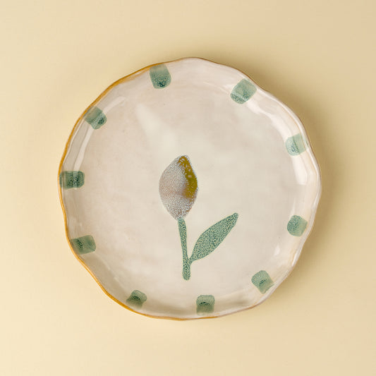 Cream stoneware plate with a hand-painted yellow tulip and green dot border