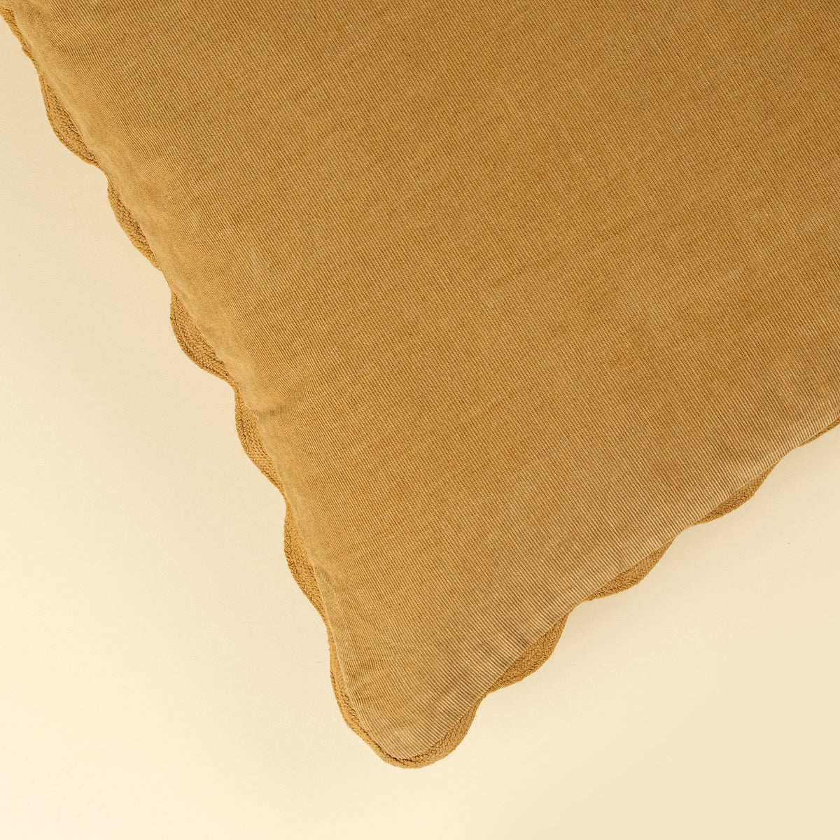 Close-up of the tone-on-tone scalloped edge on the Corduroy Scallop Pillow in Gold