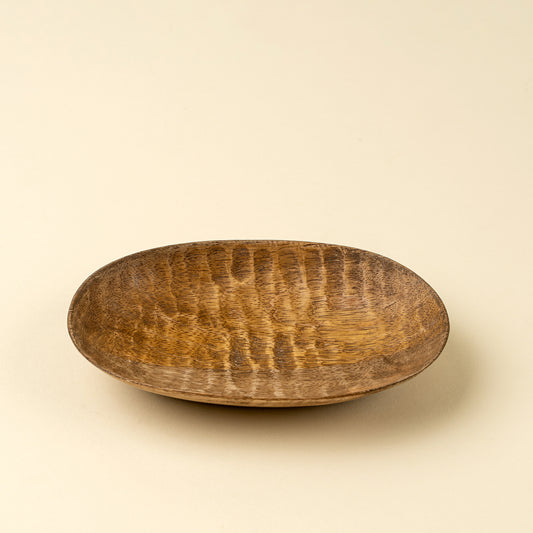Small oval hand-carved mango wood dish showing natural grain texture