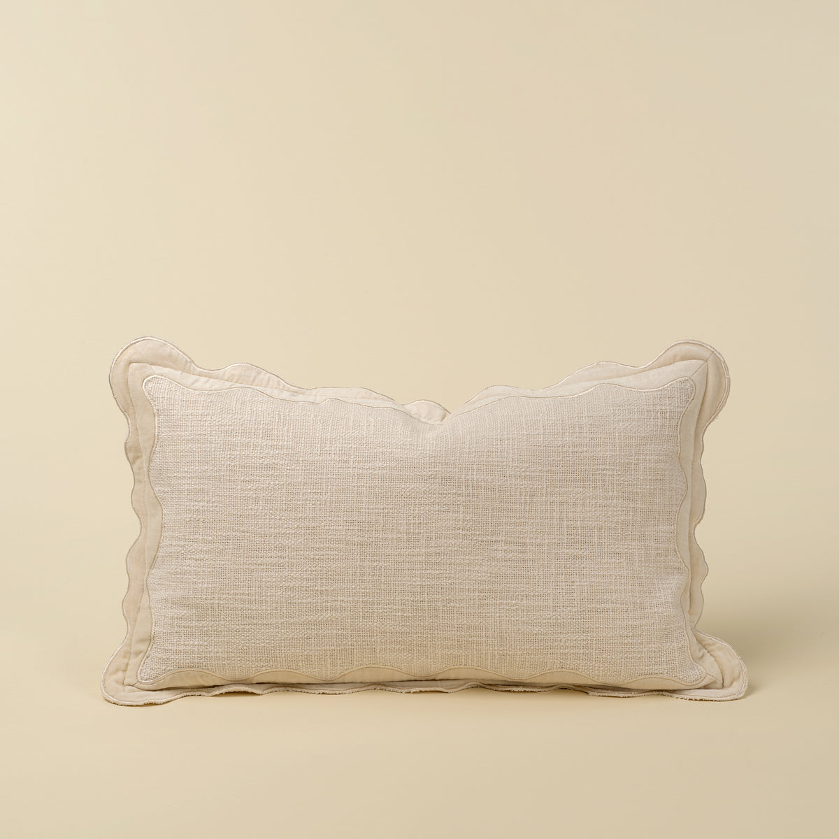 Rectangular ivory pillow with a scalloped velvet border and textured cotton body
