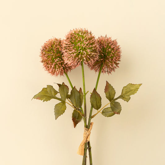 Bouquet of pink faux allium flowers with spherical blooms and green leaves tied with raffia