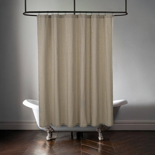 Black and cream ticking stripe shower curtain hung above a white clawfoot bathtub