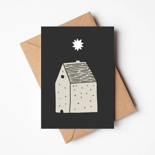 'Starry Night' new home card featuring a white star and cream illustrated house on a black background, propped against a kraft envelope