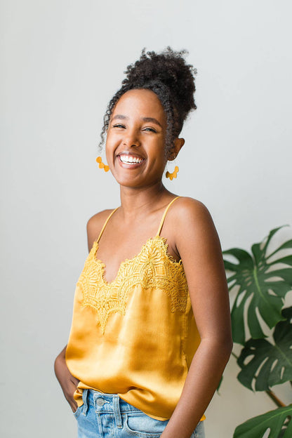 Mustard yellow leather petal hoop earrings styled with a neutral outfit