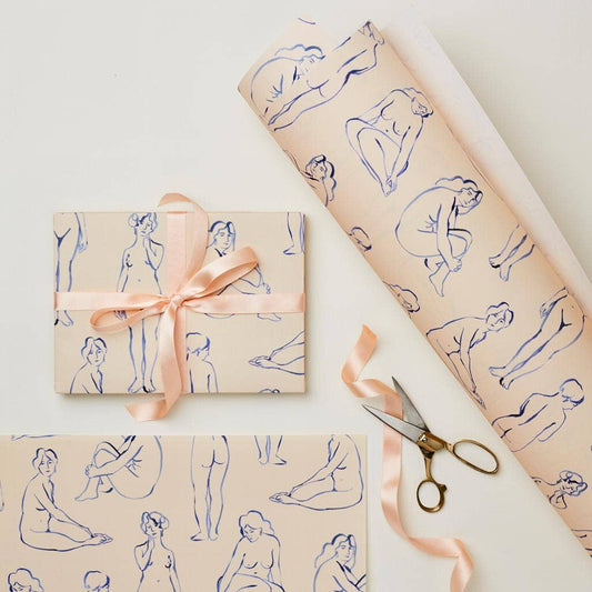 Wrapping paper printed with blue line-art nude figures on a blush pink background, tied with peach ribbon