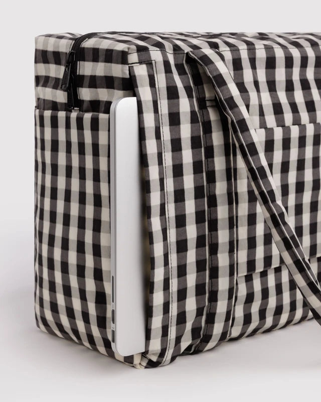 Model carrying the BAGGU Small Cloud Carry-On in black and cream gingham over one shoulder