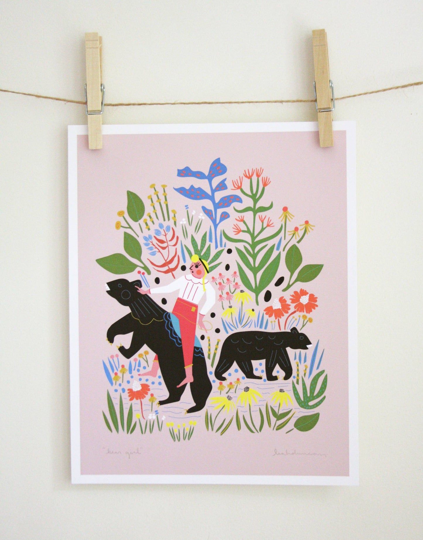 Art print of a woman walking with two black bears through wildflowers on a dusty pink background, clipped to a string — PABOOM