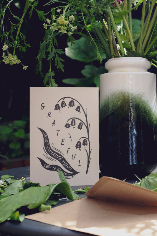 'Grateful' card standing upright with its kraft envelope, showing the full botanical illustration