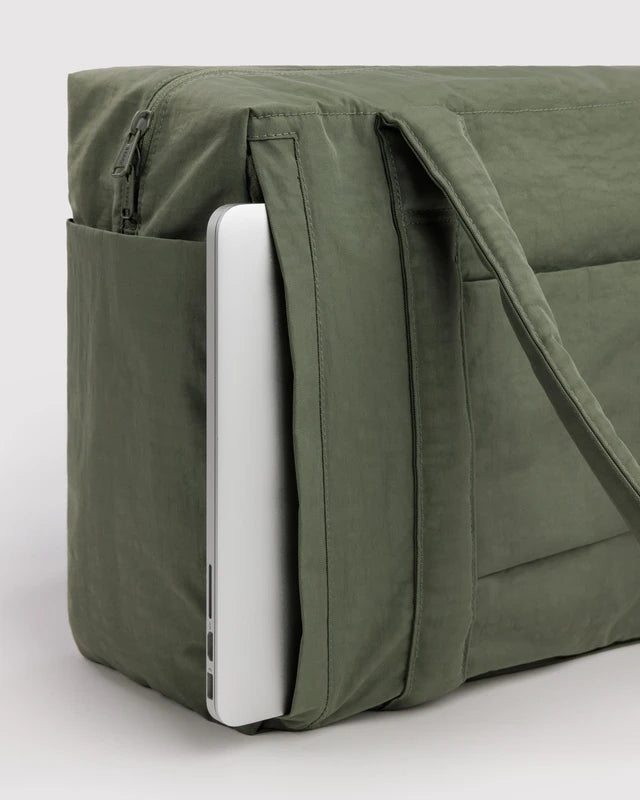 BAGGU Small Cloud Carry-On in caper green shown fitting under an airplane seat
