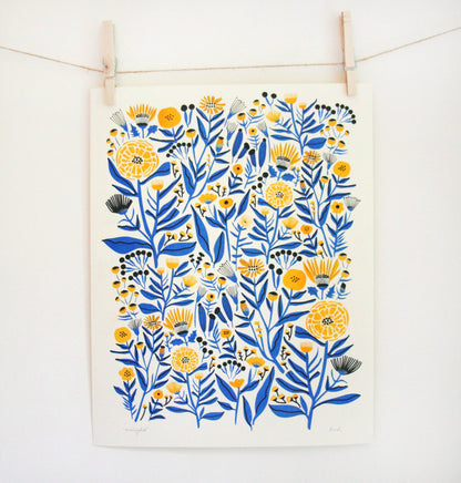 Riso print of blue and golden-yellow marigold pattern on cream paper, clipped to a string — PABOOM