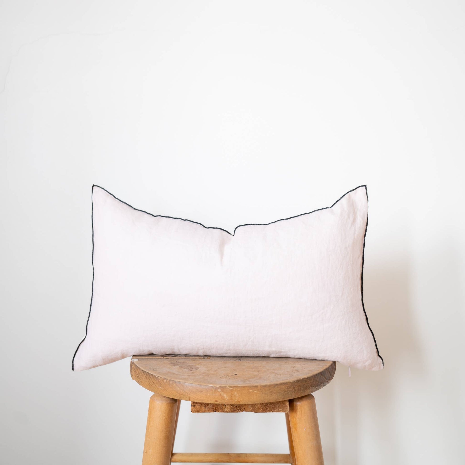 Close-up of the blush linen lumbar pillow cover showing the stonewashed flax linen texture and contrast-edge trim