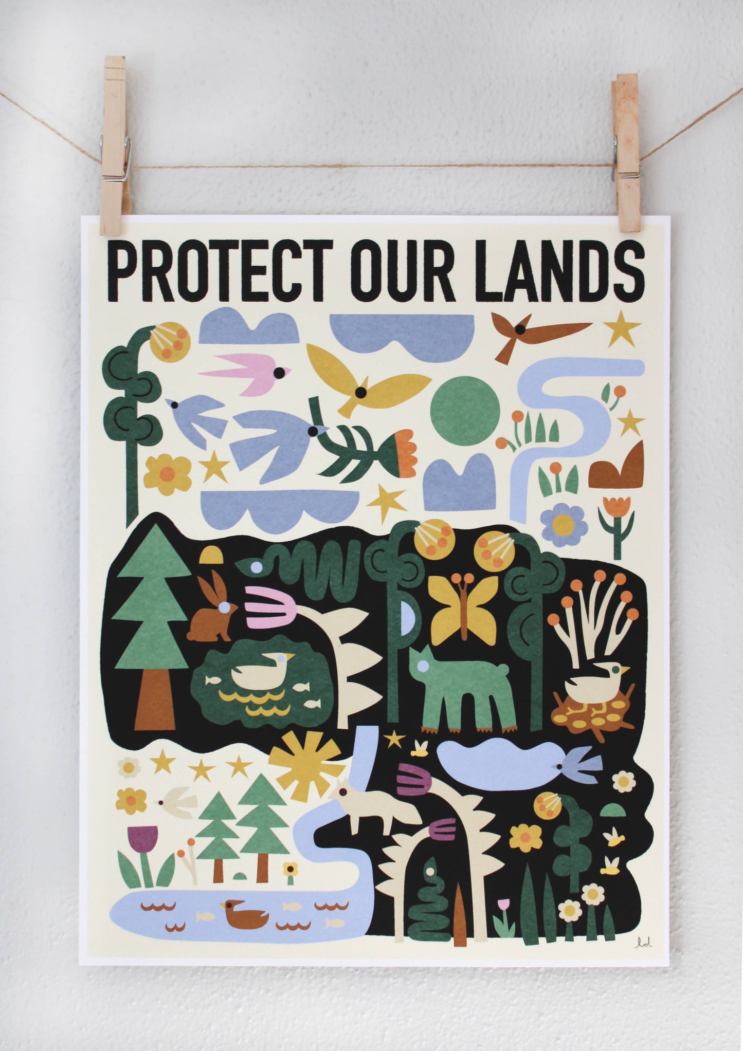 Protect Our Lands archival print with a folk-art forest and river scene featuring deer, rabbits, and birds, clipped to a string — PABOOM