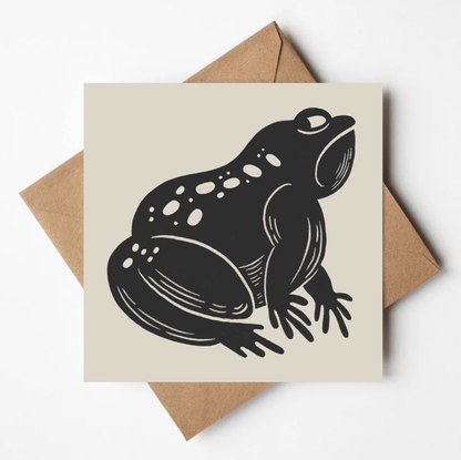 'The Grumpy Frog' animal card featuring a bold black illustration of a scowling toad on a cream square card, propped on a kraft envelope