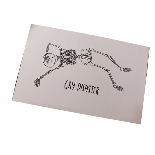 Hand-drawn illustrated print of two skeletons kissing head to head with the hand-lettered words Gay Disaster below, on cream cardstock
