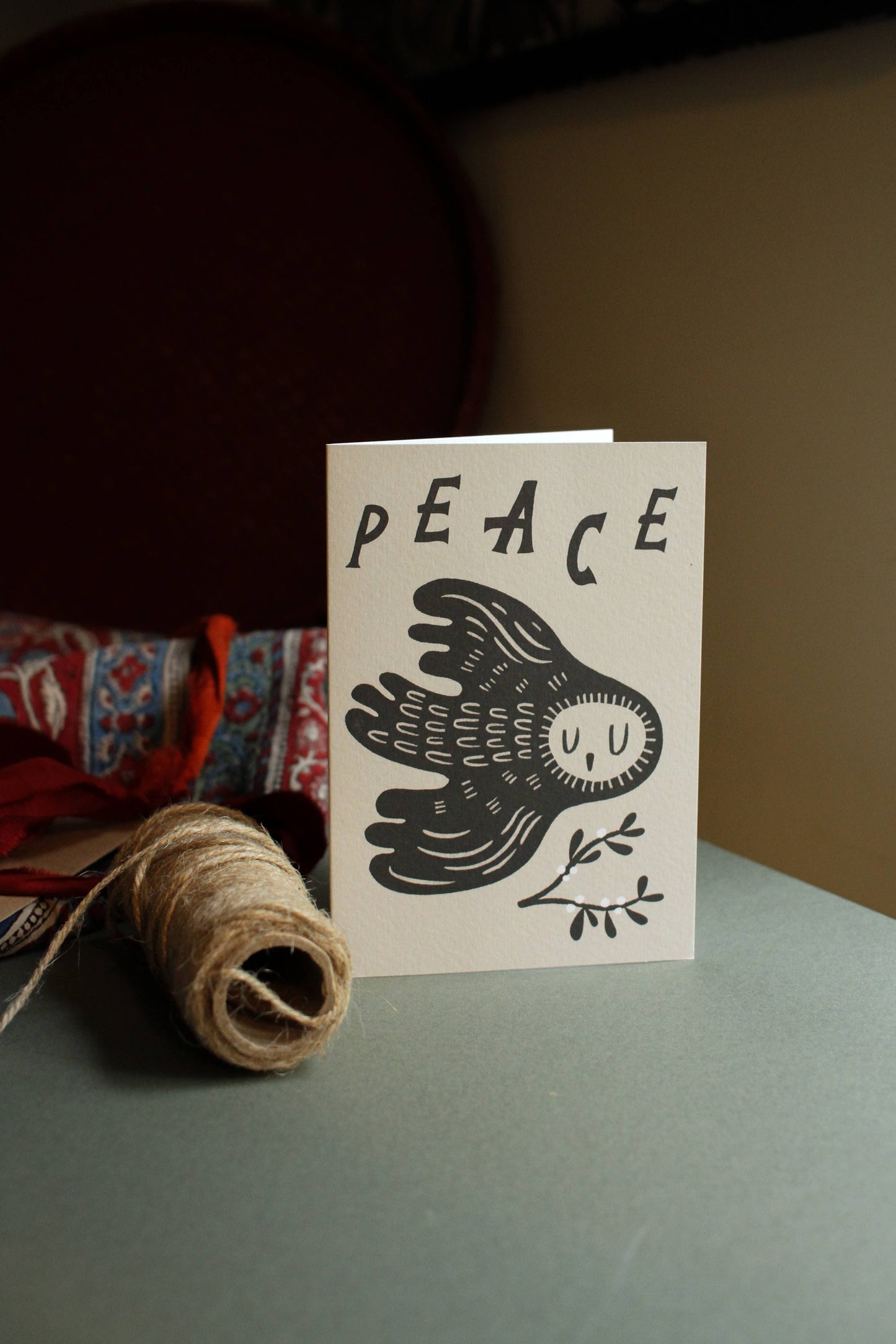 'Peace' sleepy owl Christmas card with its kraft envelope on a light background