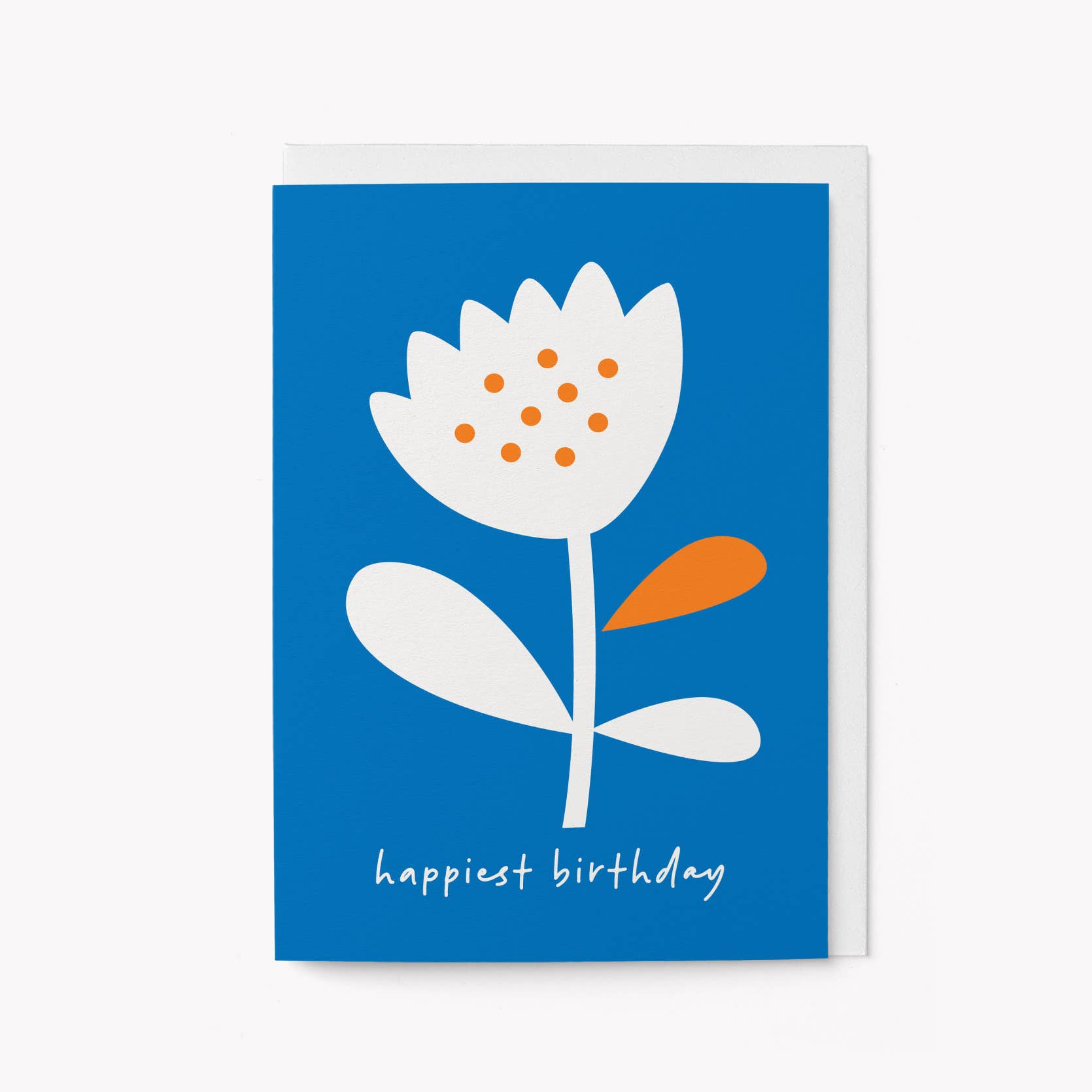 Bold blue greeting card with a graphic white flower with orange dotted centre and an orange petal, and 'happiest birthday' written in script