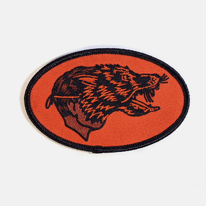 Oval iron-on patch with an embroidered snarling wolf head on an orange background - PABOOM