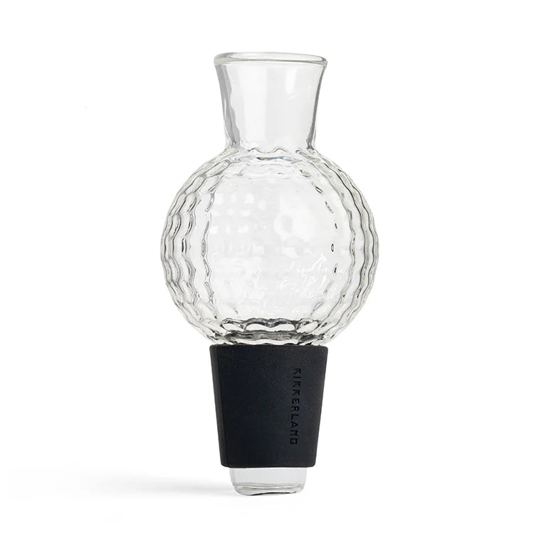 Clear glass golf-ball-shaped wine aerator with textured dimpled surface and black silicone stopper base.