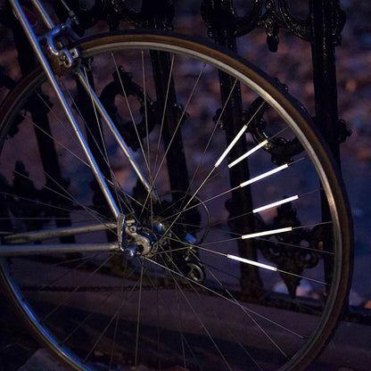 Bike spoke reflector shown snapped onto a wheel spoke.