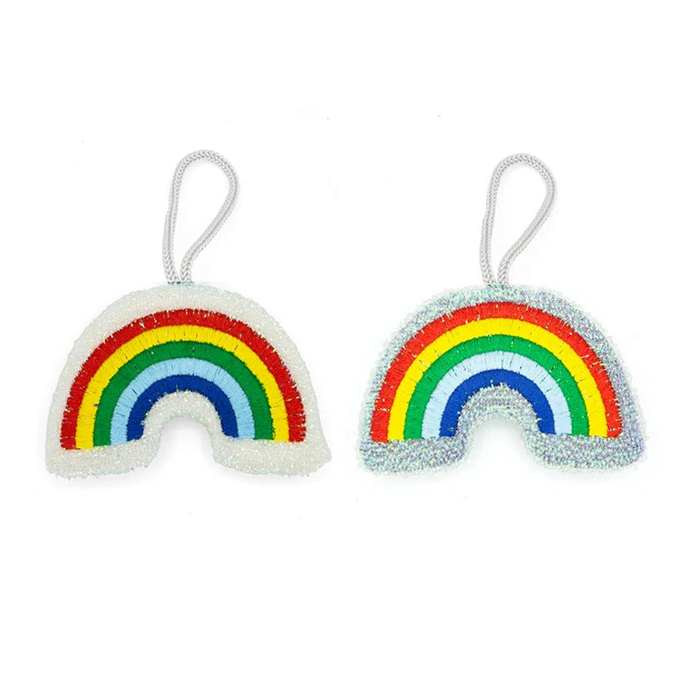 Two rainbow-shaped beaded scrub sponges with hanging loops, one in pastel tones and one iridescent.