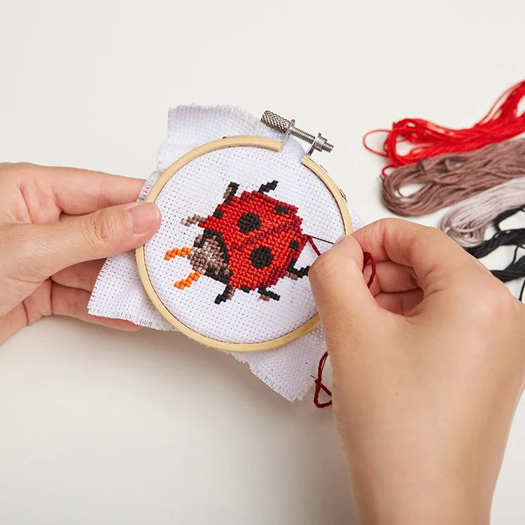Completed ladybug cross stitch pattern in bamboo hoop frame.