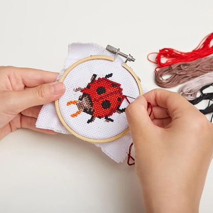 Completed ladybug cross stitch pattern in bamboo hoop frame.