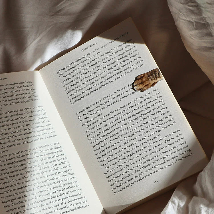 Magnetic cat paw bookmark clipped onto a book page.