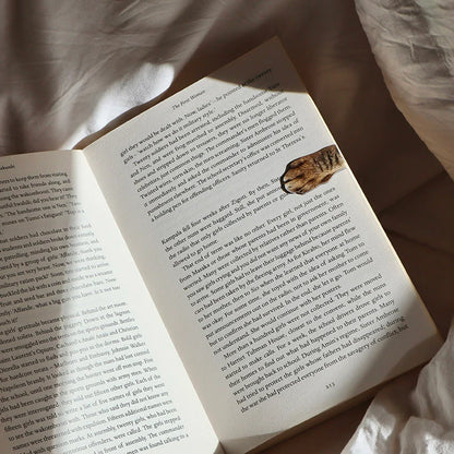 Magnetic cat paw bookmark clipped onto a book page.