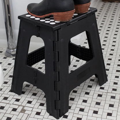 Tall black folding step stool shown from the side, demonstrating locking hinge mechanism.