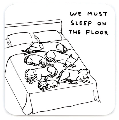 David Shrigley line drawing of dogs sprawled across a bed captioned "We must sleep on the floor," printed on a coaster - PABOOM