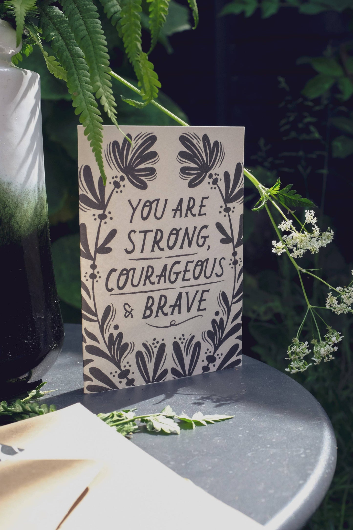 'Strong, Courageous & Brave' card with kraft envelope on a light background
