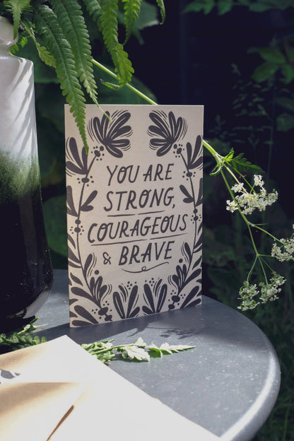 'Strong, Courageous & Brave' card with kraft envelope on a light background
