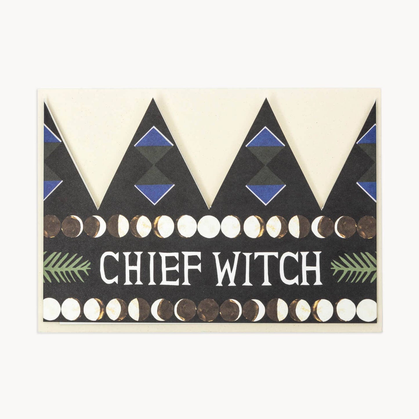 Black party hat crown card with a blue diamond pattern, a row of moon-phase circles, and the text 'CHIEF WITCH' in white flanked by green fern illustrations