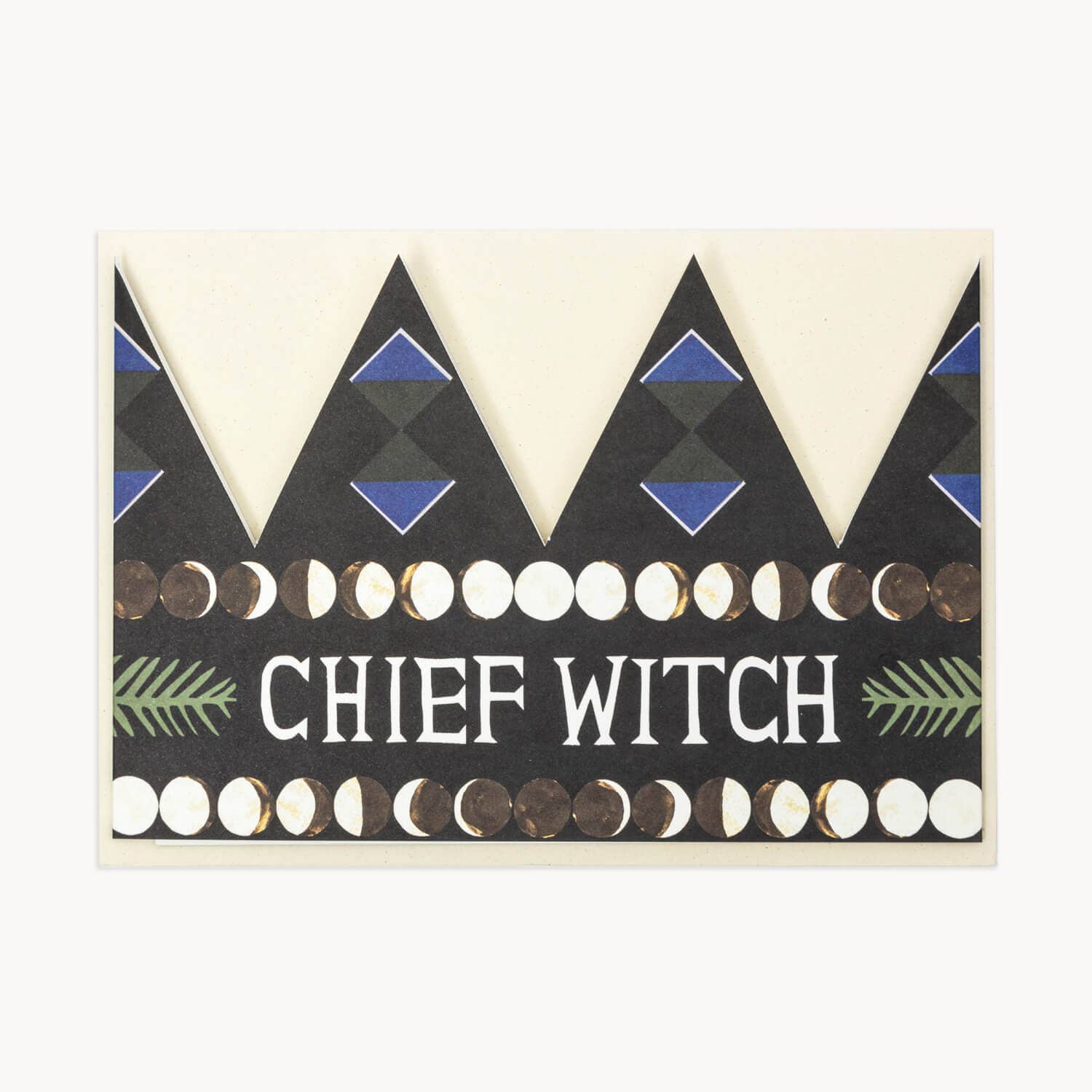 Black party hat crown card with a blue diamond pattern, a row of moon-phase circles, and the text 'CHIEF WITCH' in white flanked by green fern illustrations