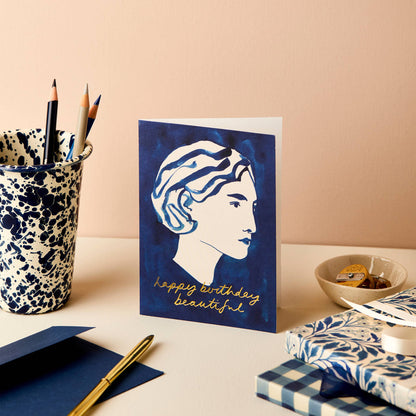 Deep blue card with a white line portrait of a woman, reading Happy Birthday Beautiful in gold script