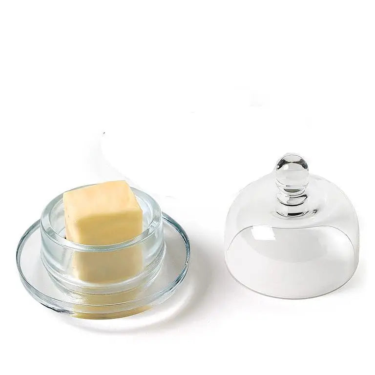 Small domed glass butter dish with lid beside stick of butter – compact and elegant tableware - PABOOM