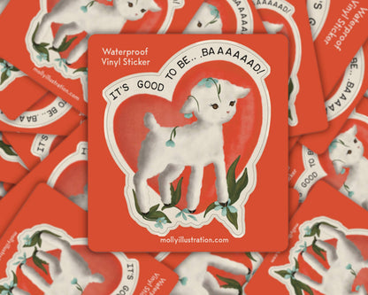 Matte vinyl sticker of a white lamb inside a heart outline on a red background with the text 'It's Good to Be Baaad'